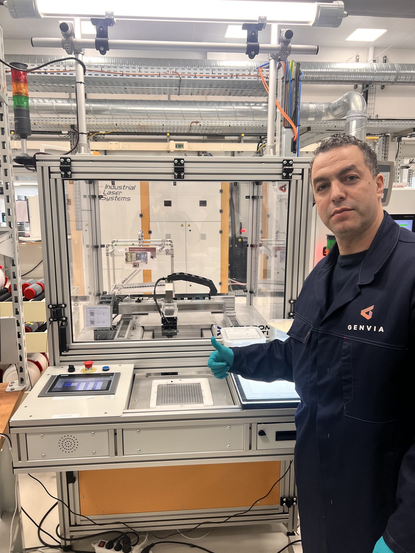 Devant une machine industrielle, en tenue Genvia