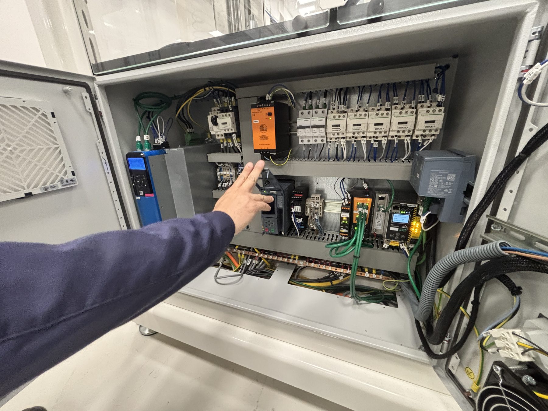 Main désignant un composant dans une armoire électrique
